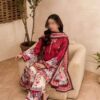 Full view of a woman wearing Firdous Printed Lawn 3 Piece Suit sitting gracefully on a sofa, showcasing deep purple printed lawn fabric and printed voile dupatta